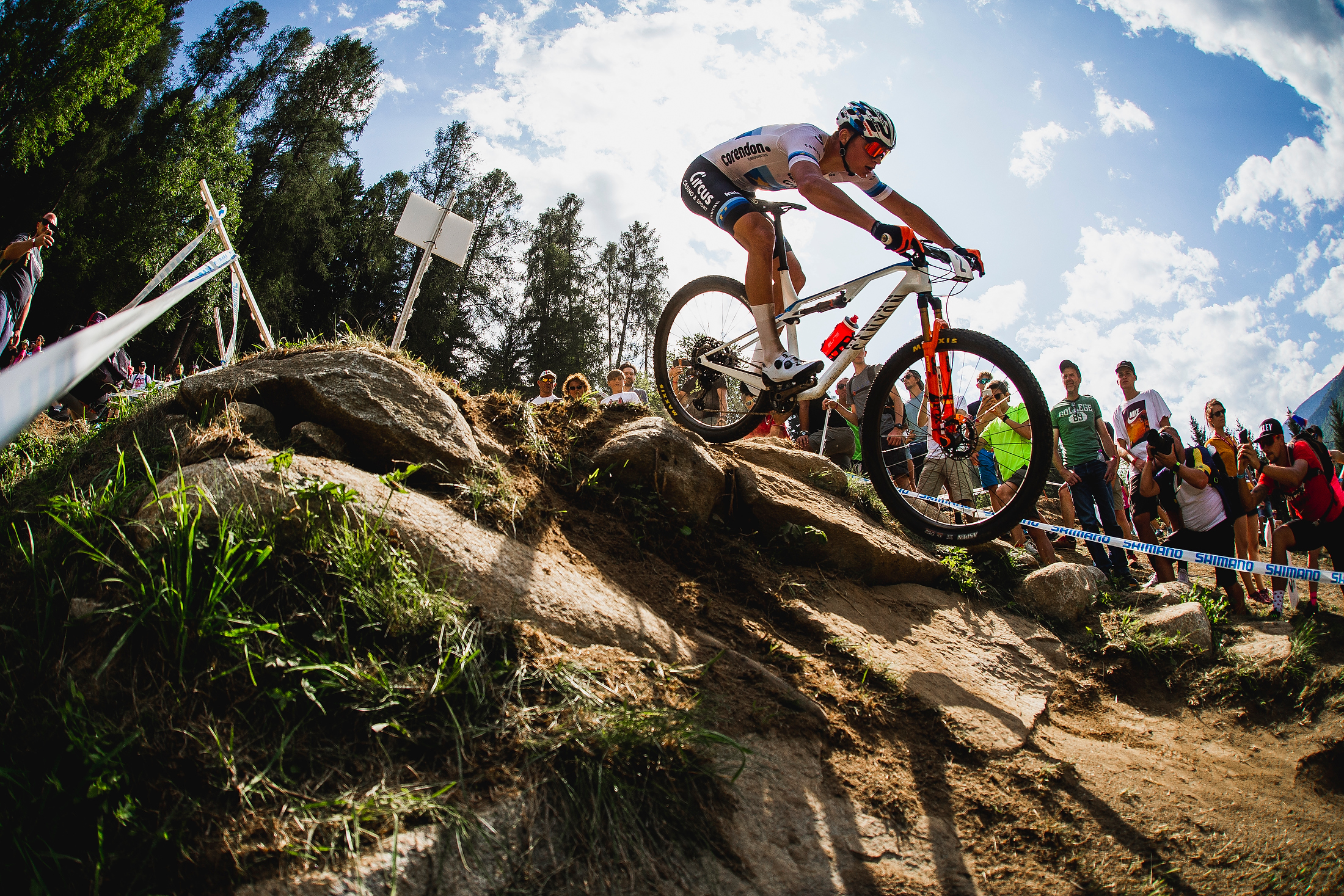 Mathieu Van der Poel leans back and points the bike downhill over some large rocks.